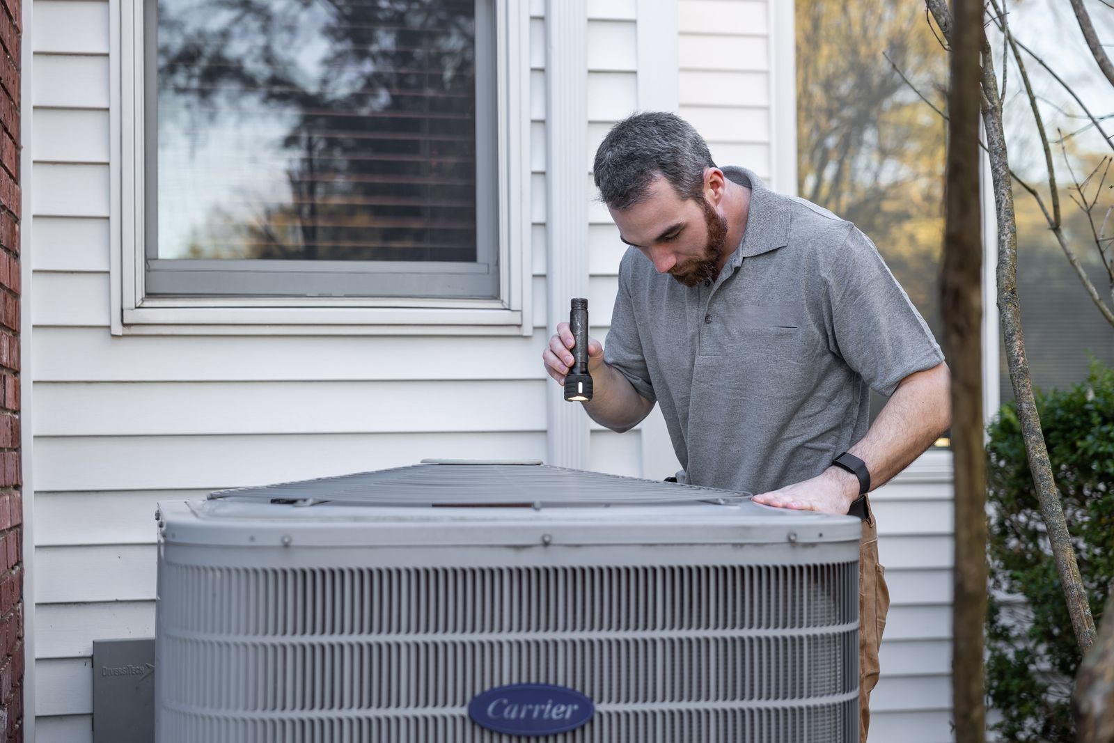 HVAC technician inspecting an outdoor unit at a customer's home